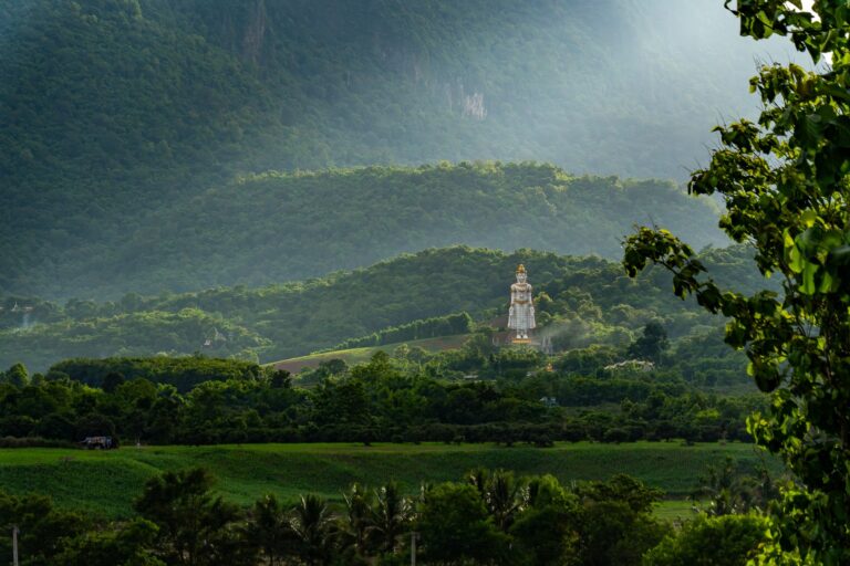 Misty hills and a hilltop Buddha statue on a Siam Bike Tours cycling route in Thailand