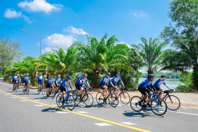 Cyclists riding along a scenic coastal road in Thailand with Siam Bike Tours