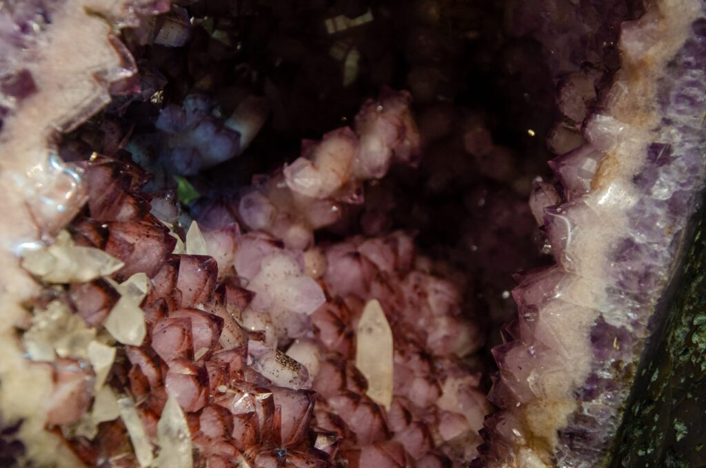 Close-up of crystal terminations inside a geode, purple and pink amethyst points with a few clear crystals