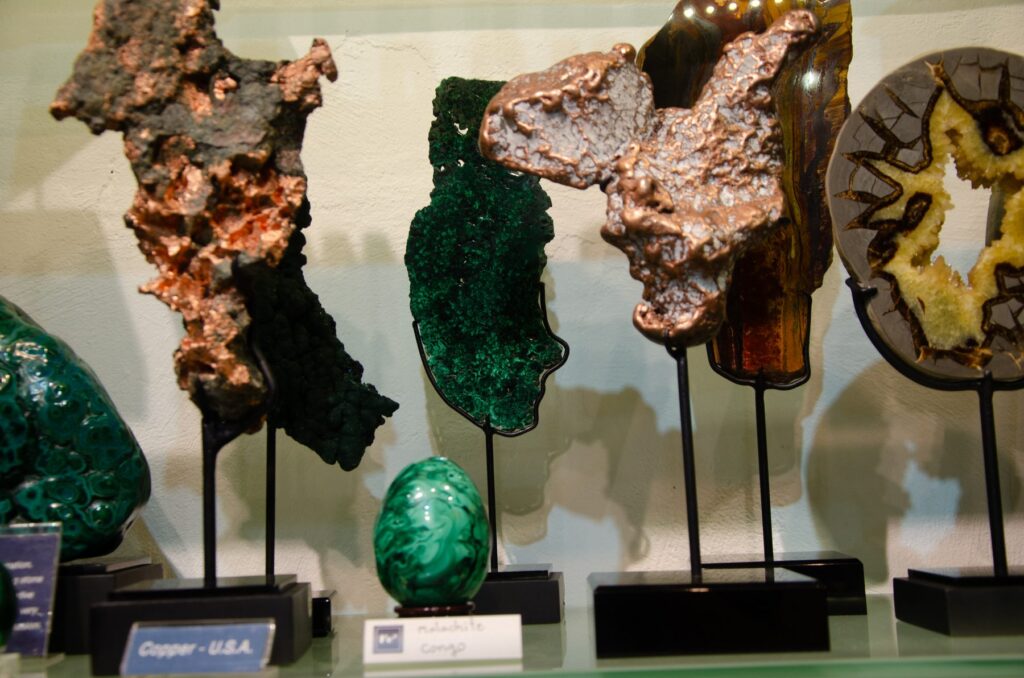 Copper, malachite and a septarian slice on black stands, with labels naming their origin