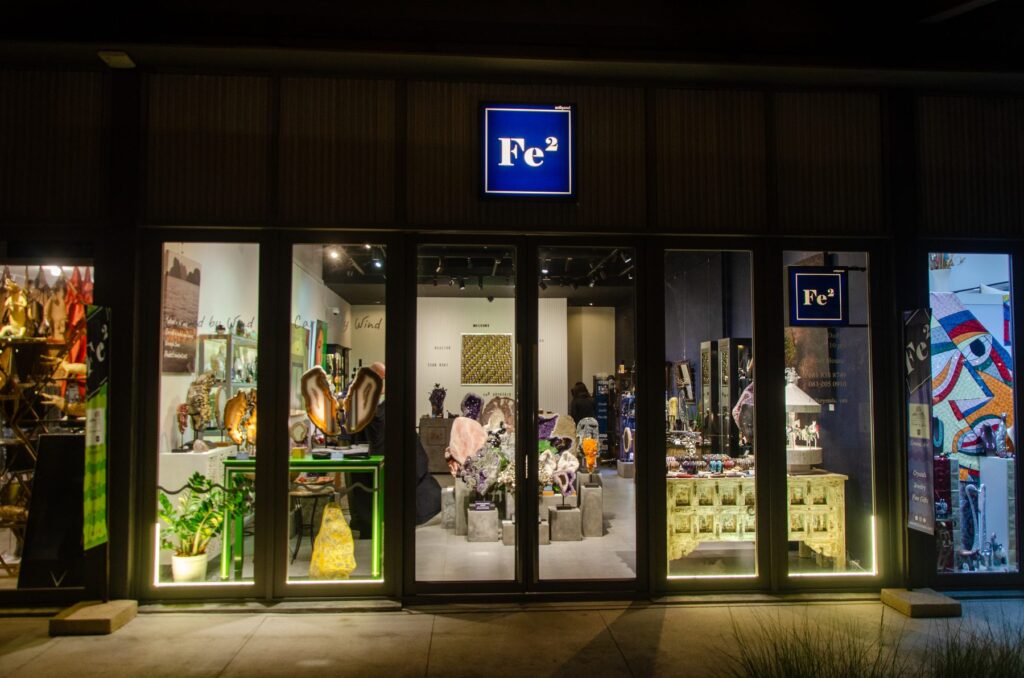 The Fe2 Crystals gallery entrance at night, lit windows and the Fe2 sign above the glass doors, Porto de Phuket
