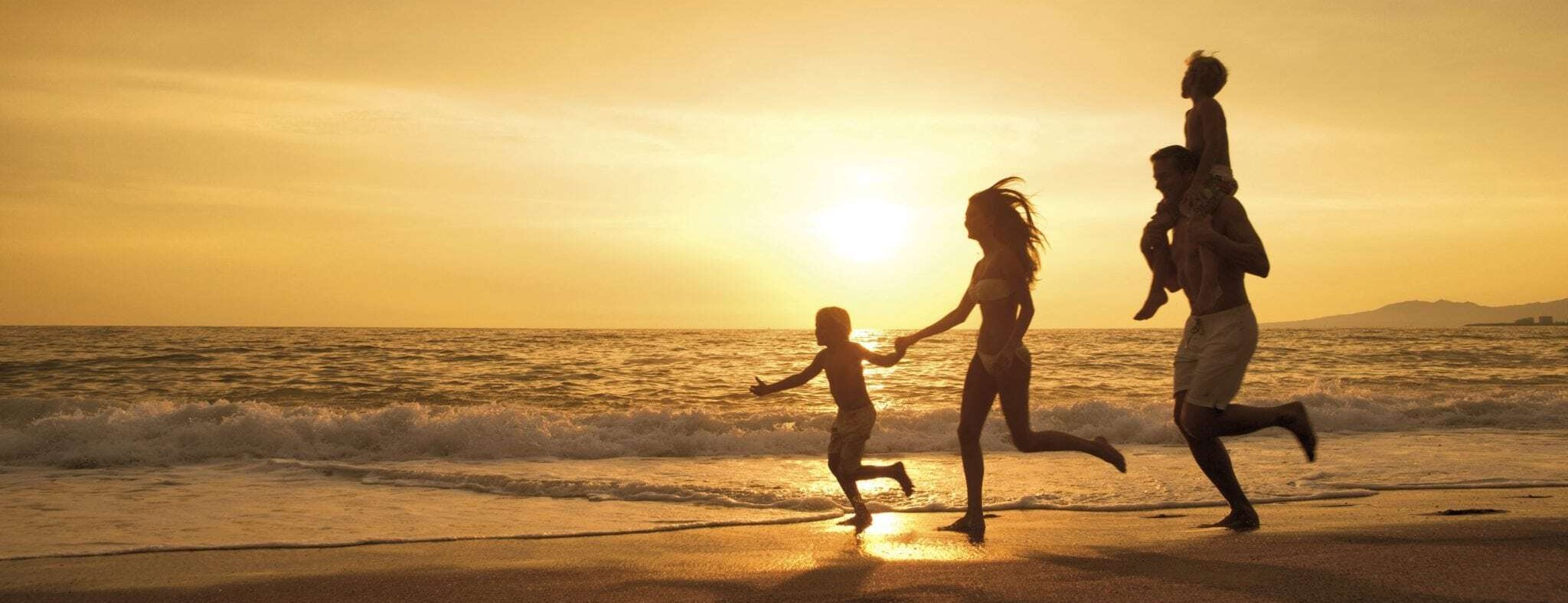 Family running along a beach at sunset