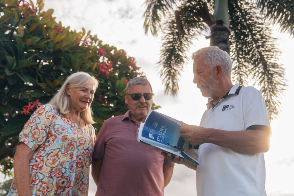 A Yacht Sales Co. broker showing a brochure to two clients