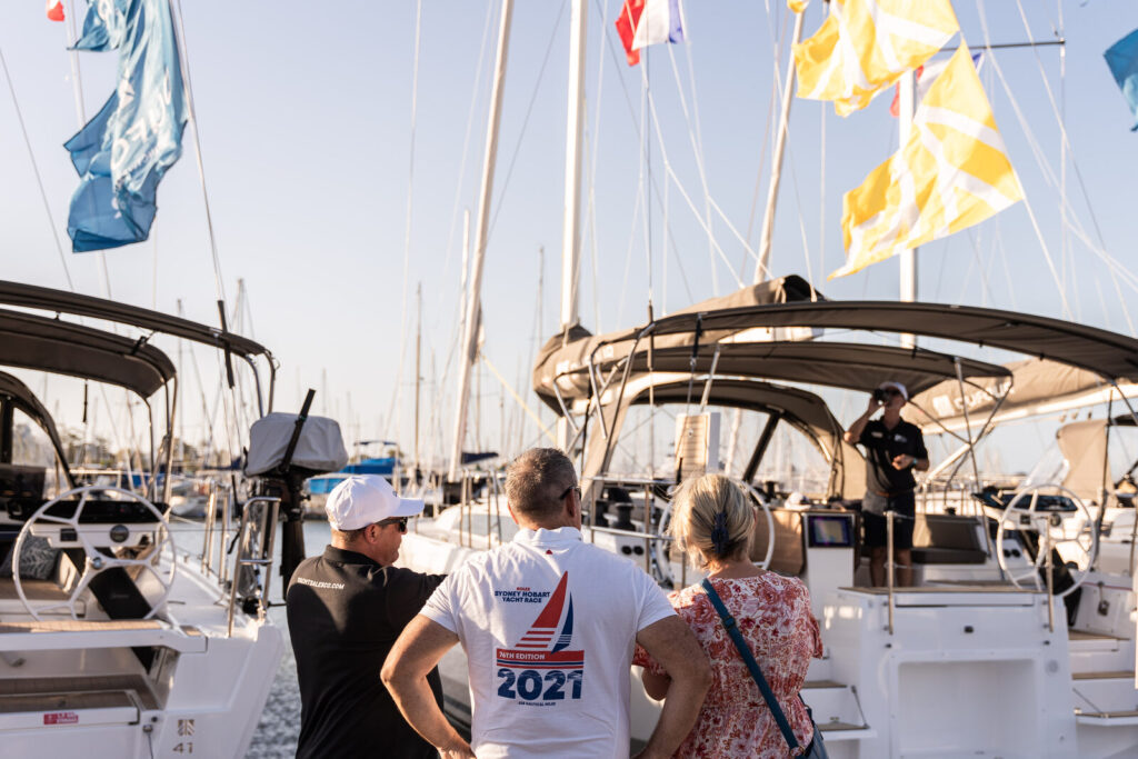 Visitors walking between yachts moored in a marina